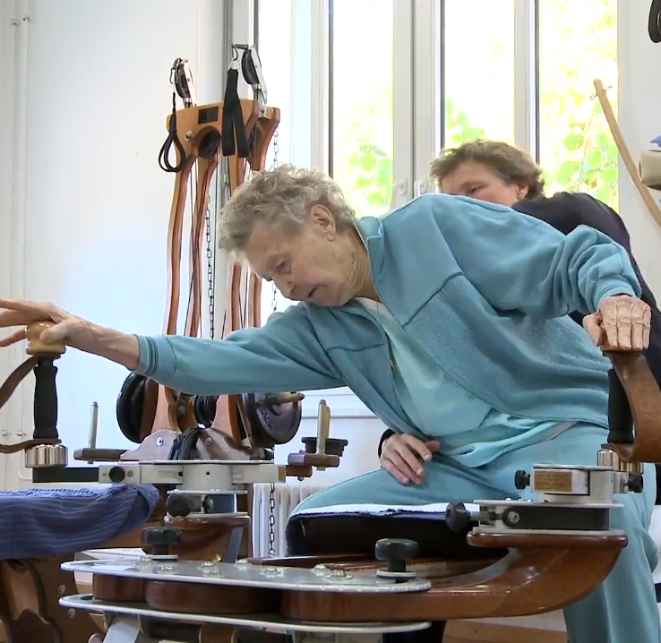 Elderly Gyrotonic exercise student being guided by a Gyrotonic instructor