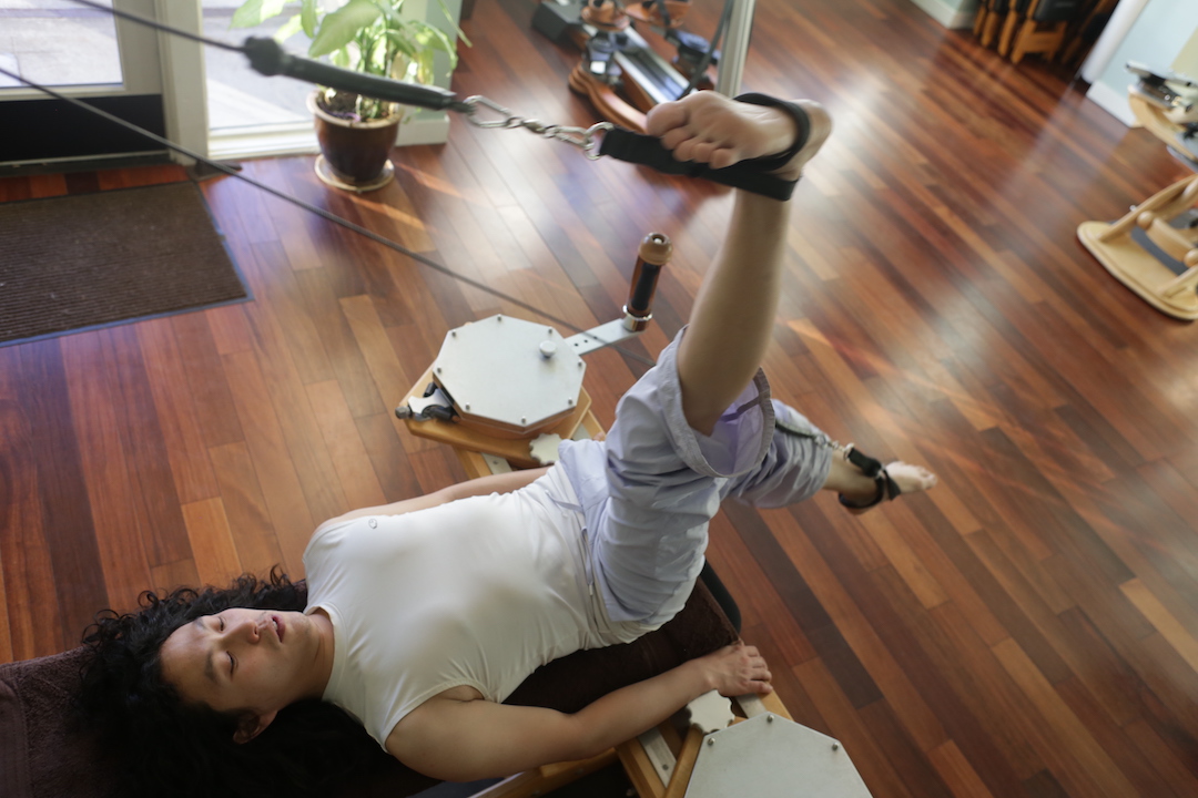 Gyrotonic Trainer Joseph Liu working his legs and hamstrings on the Gyrotonic Pully Tower Unit