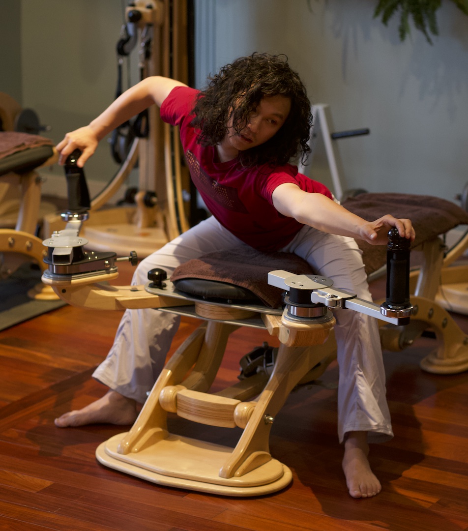 Gyrotonic Trainer Joseph Liu working the bow and arrow movement on the handles